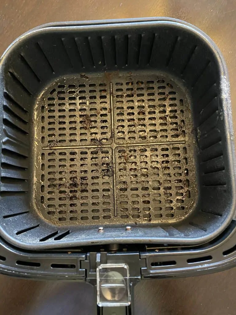 a dirty air fryer basket on a flat surface