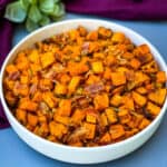 air fryer sweet potato hash with chopped bacon in a white bowl