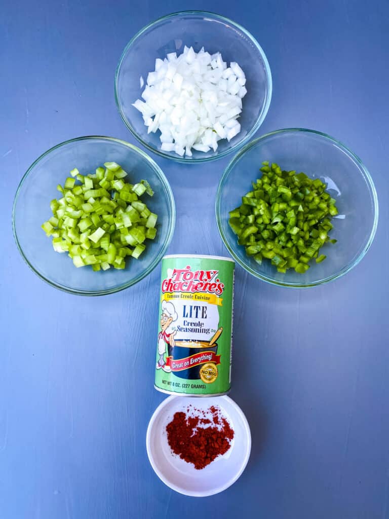 chopped onions, green peppers, green celery, and Creole seasoning on a flat surface