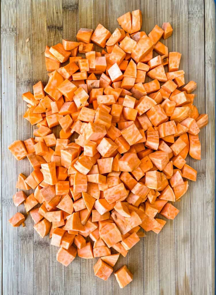 diced, raw sweet potatoes on a bamboo cutting board