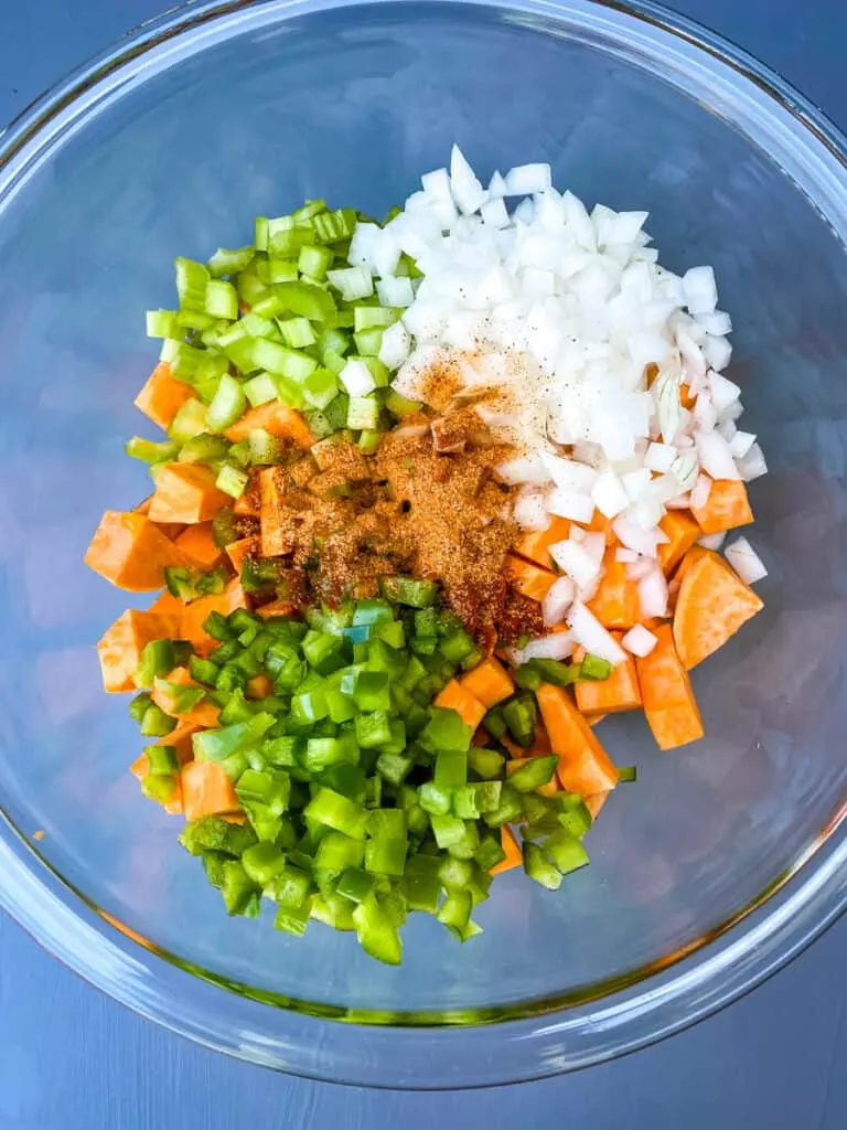 diced sweet potatoes, onions, green peppers, and celery in a glass bowl