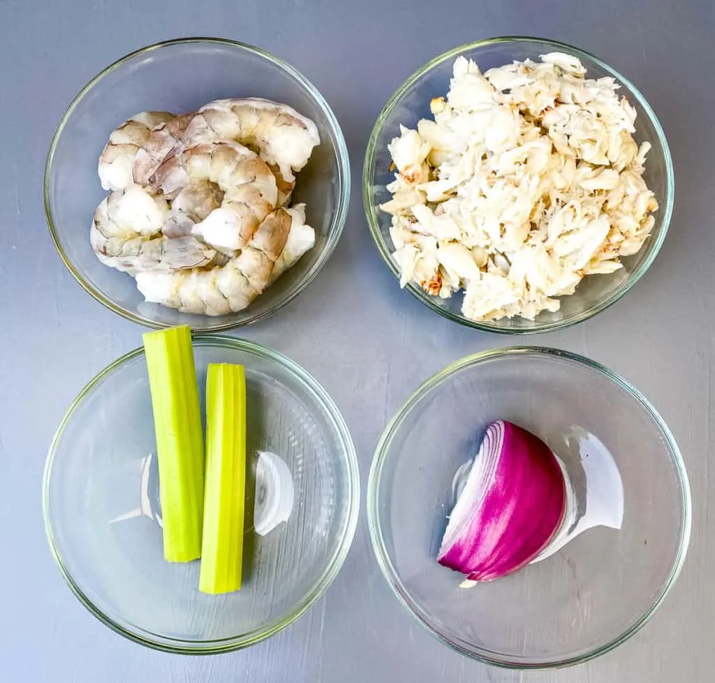 raw shrimp, lump crab, raw celery, and raw onions in separate glass bowls