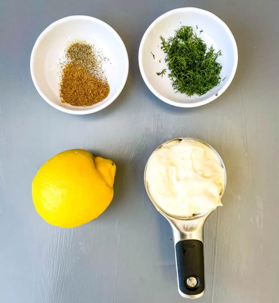 Old Bay seasoning, fresh dill lemon, and mayo on a flat surface