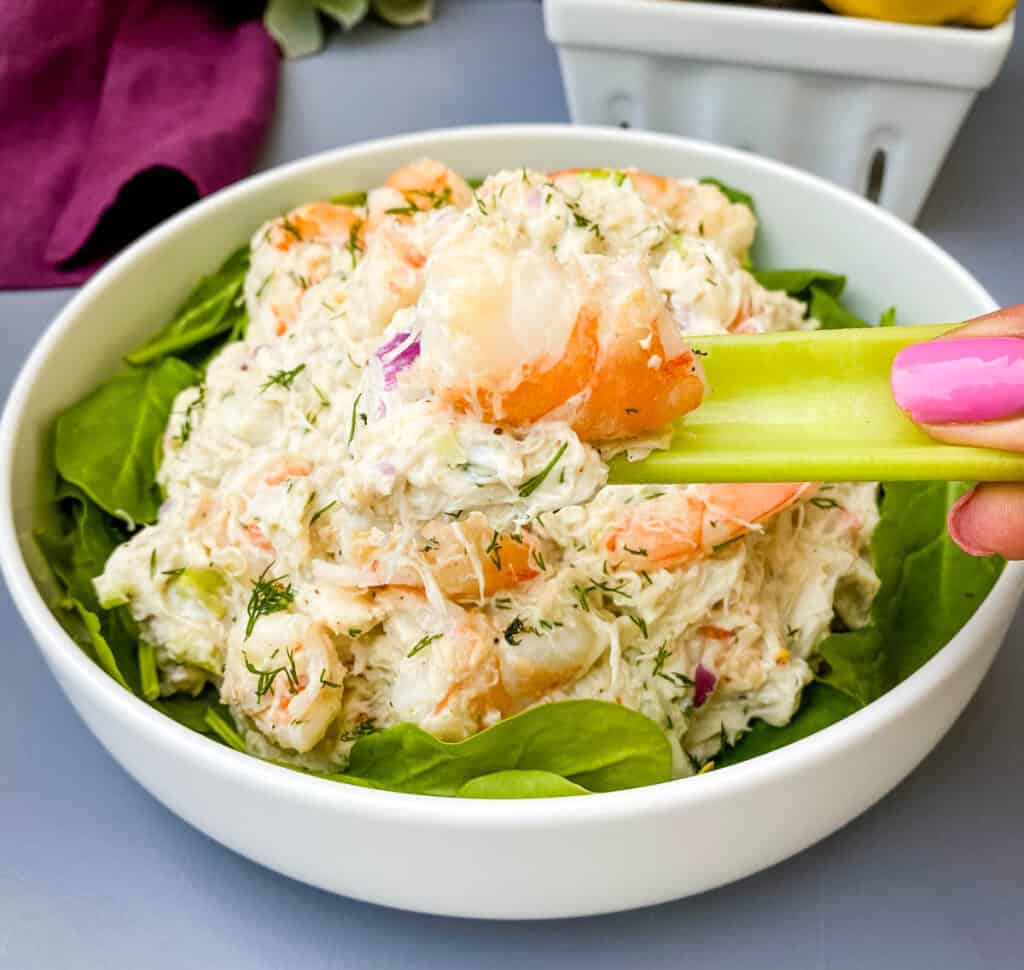 person holding a stalk of celery with seafood salad