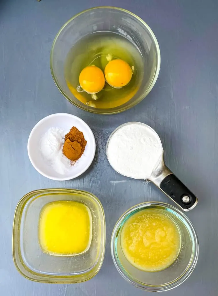 raw eggs, cinnamon, sweetener, melted butter, and unsweetened applesauce on a flat surface