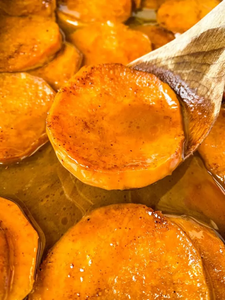 a spoonful of southern candied sweet potato yams in a baking dish