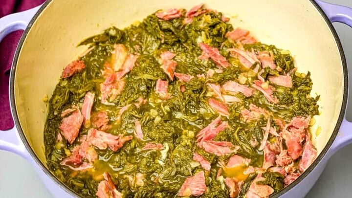 cooked southern mustard green with a smoked turkey leg in a Dutch oven