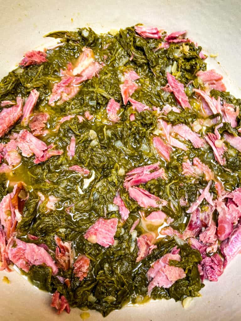 cooked southern mustard green with a smoked turkey leg in a Dutch oven