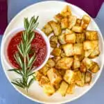 air fryer roasted potatoes on a white plate with ketchup