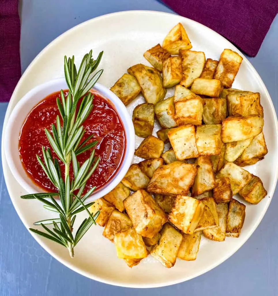 air fryer roasted potatoes on a white plate with ketchup