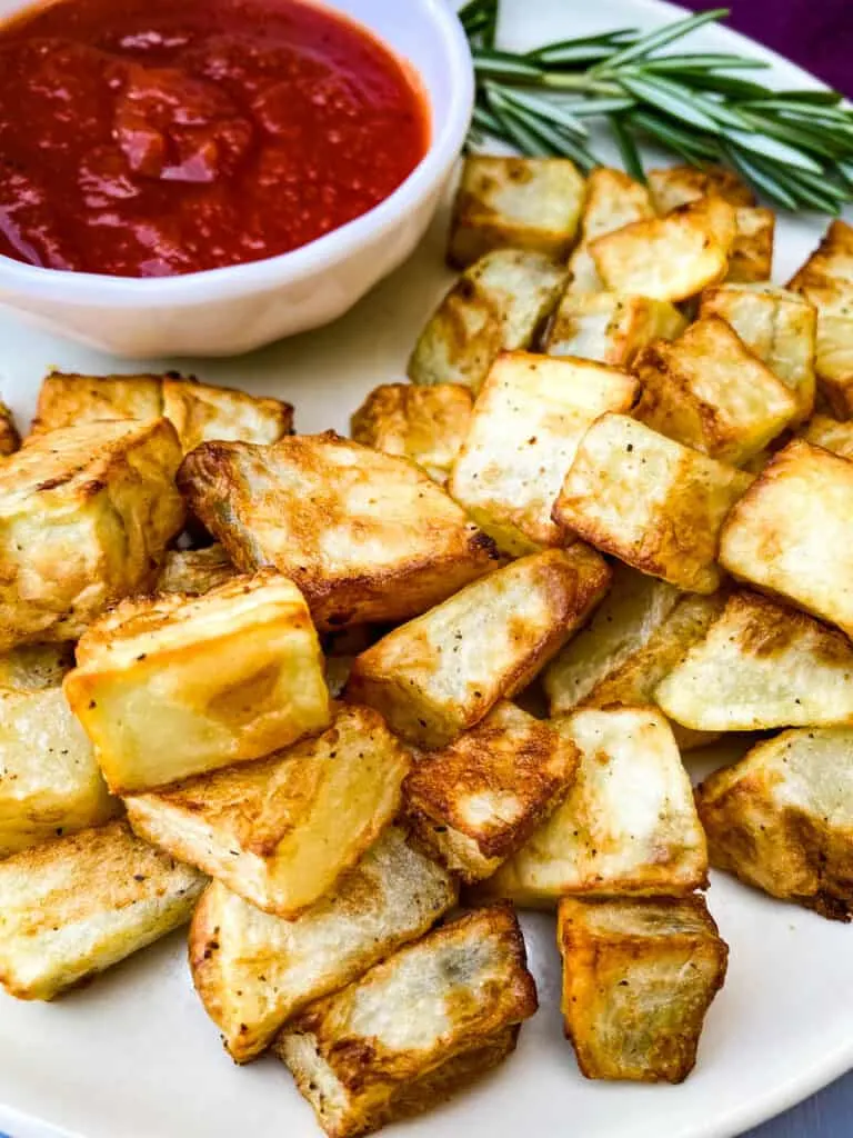 air fryer roasted potatoes on a white plate with ketchup