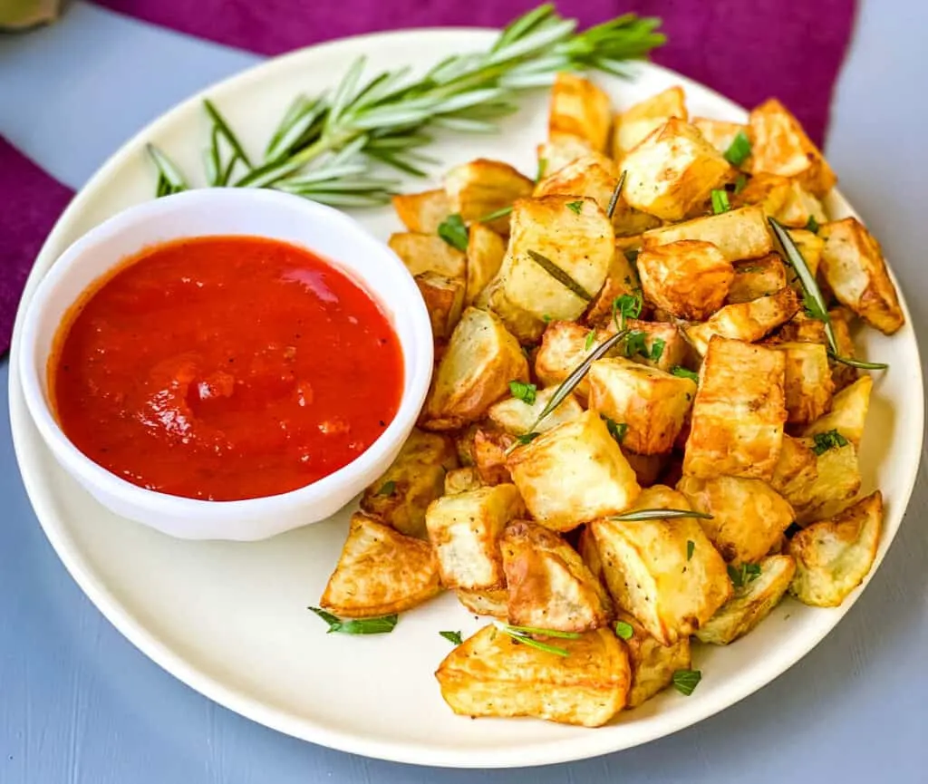 air fryer roasted potatoes on a white plate with ketchup