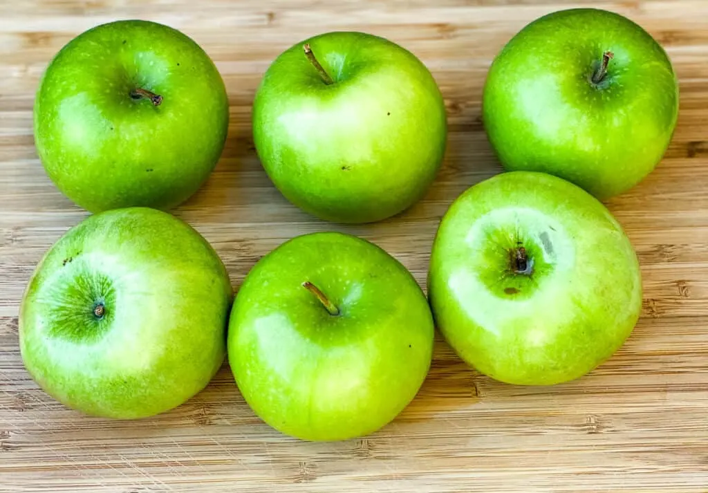 Granny Smith apples on a bamboo cutting board