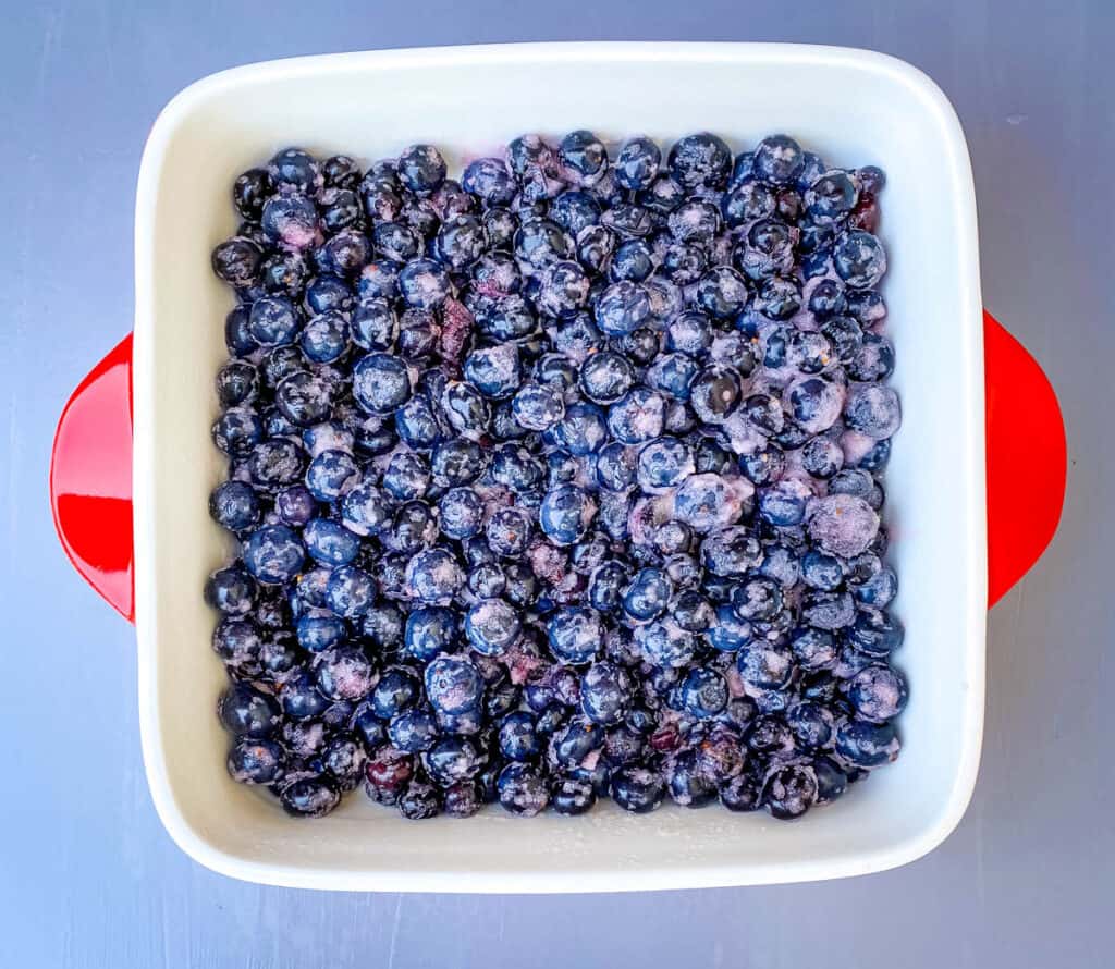 blueberry crisp filling in a red baking dish