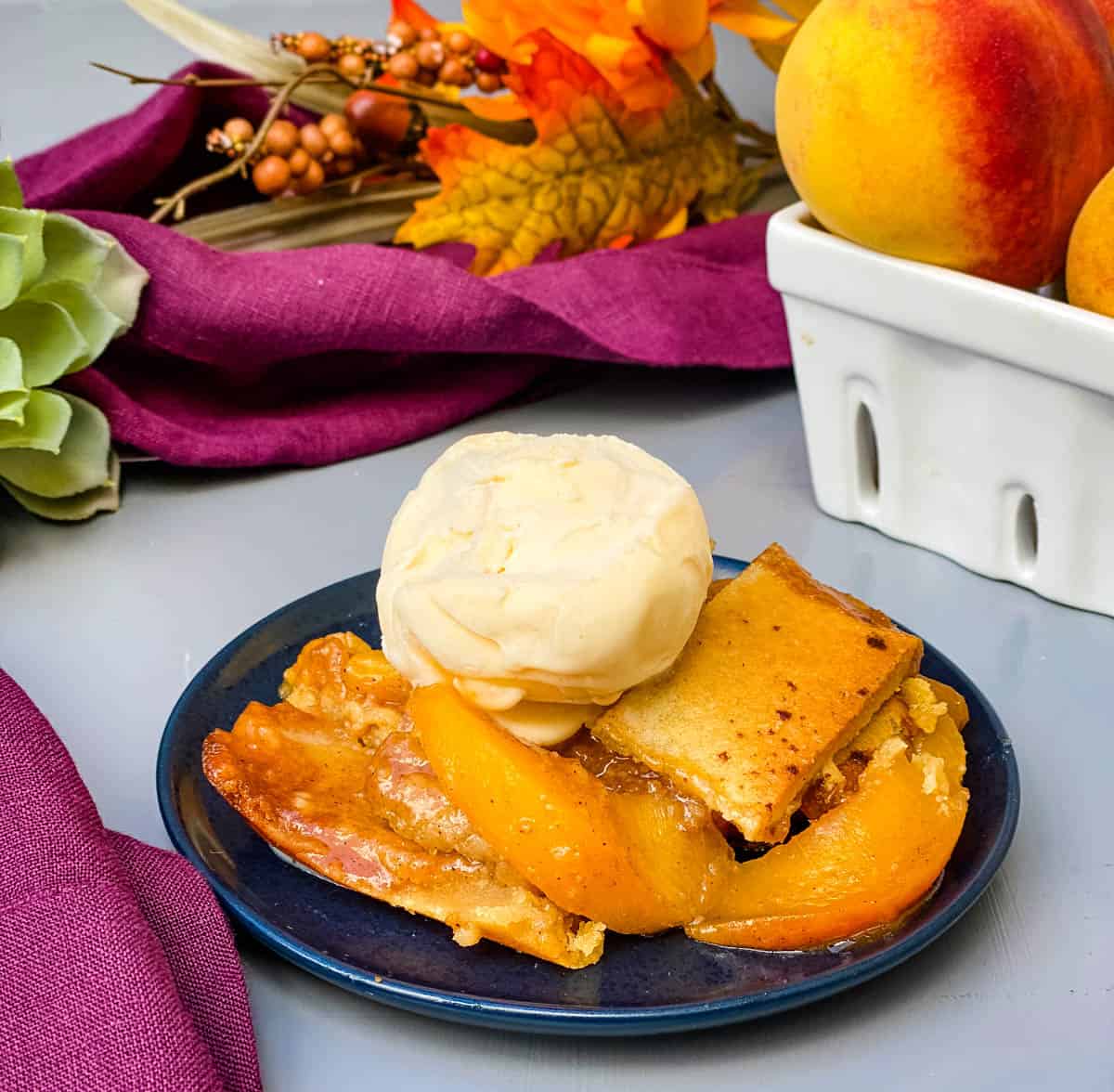 healthy southern peach cobbler on a blue plate with vanilla ice cream