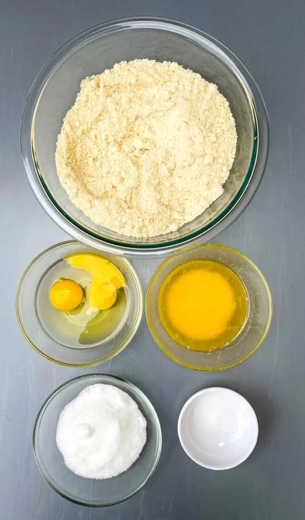 almond flour, raw eggs, melted butter, sweetener and salt in bowls on a flat surface