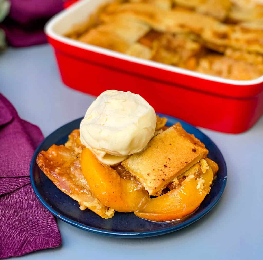 healthy southern peach cobbler on a blue plate with vanilla ice cream