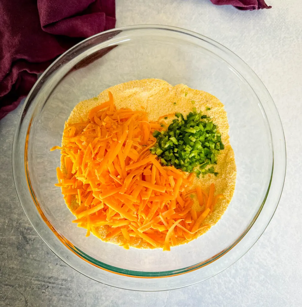 cornmeal, cheddar cheese, jalapenos, baking powder, and flour in a glass bowl