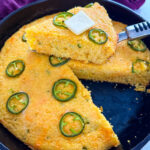 jalapeno cheddar cornbread with butter in a cast iron skillet