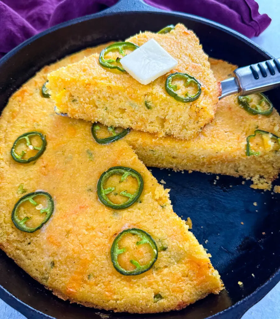 jalapeno cheddar cornbread with butter in a cast iron skillet