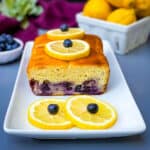 keto low carb lemon blueberry bread on a white plate with fresh lemons and blueberries