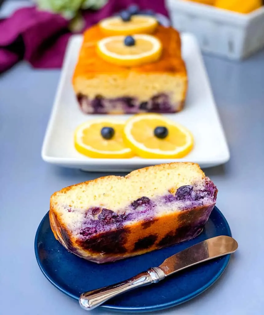 keto low carb lemon blueberry bread on a white plate with fresh lemons and blueberries