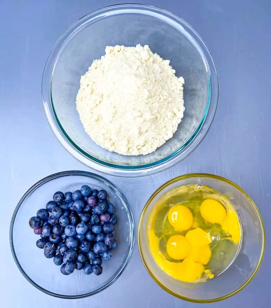 fresh blueberries, almond flour, and raw eggs in separate bowls