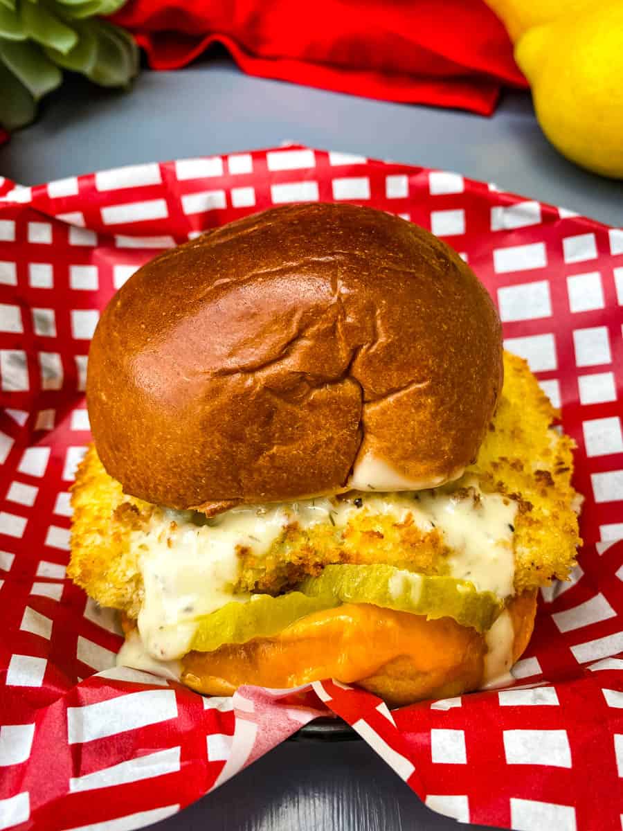 air fryer fish sandwich on a bun with melted cheese and tartar sauce