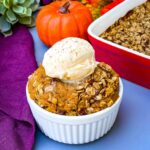 healthy pumpkin crisp in a white bowl with a scoop of vanilla ice cream