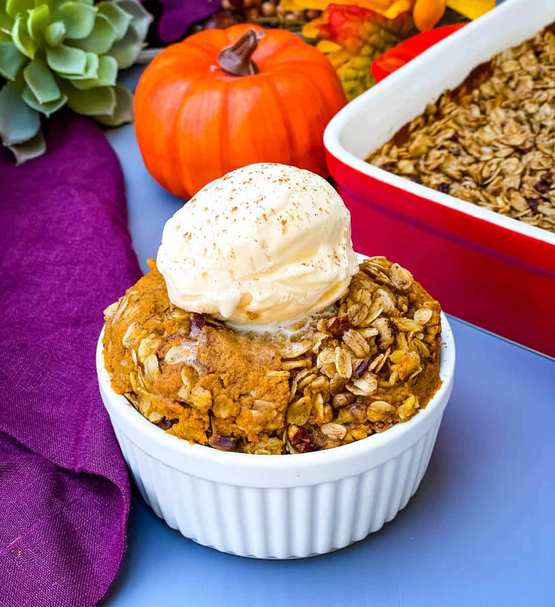 healthy pumpkin crisp in a white bowl with a scoop of vanilla ice cream
