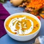 Panera copycat autumn squash soup in a white bowl with seeds and bacon