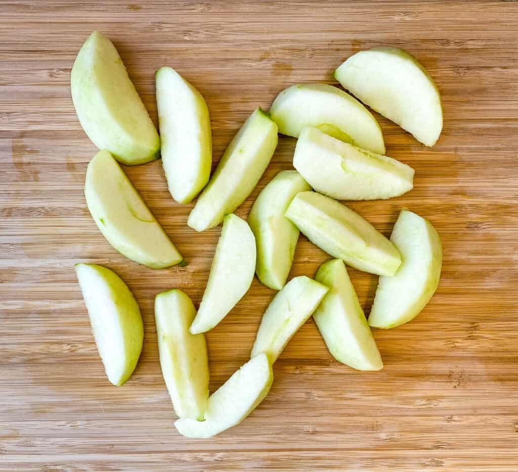 sliced Granny Smith apples on a wooden cutting board