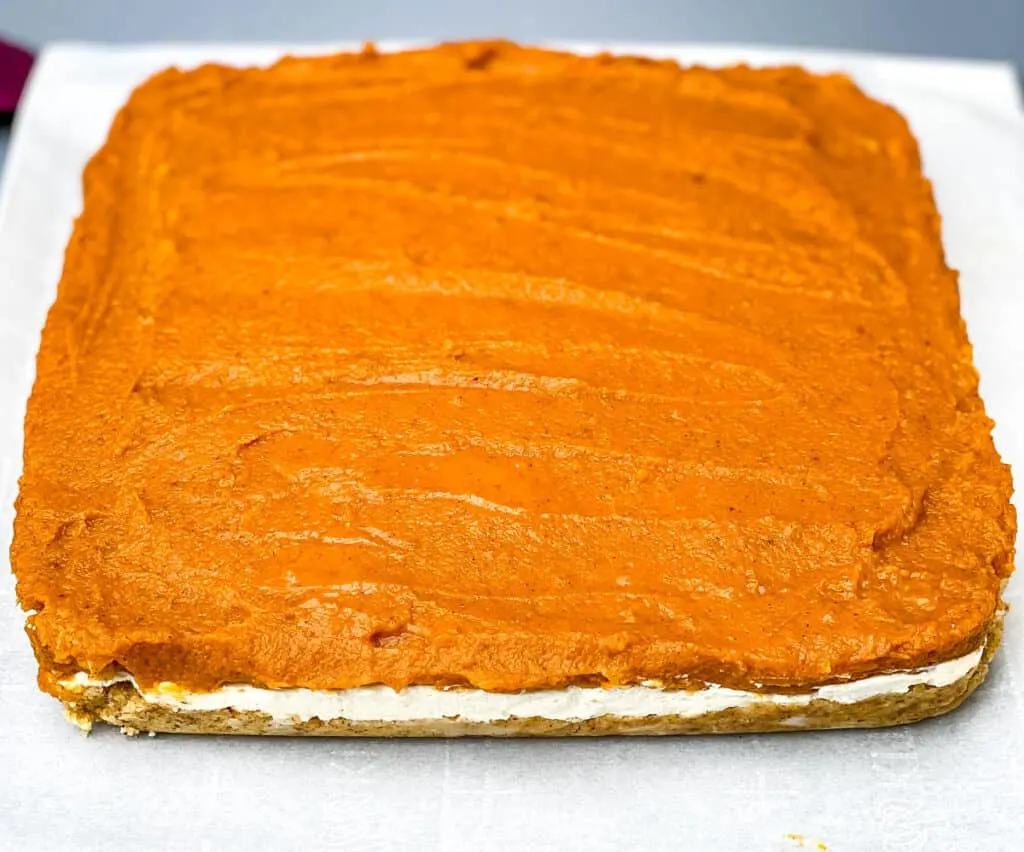 pumpkin cheesecake bars on parchment paper
