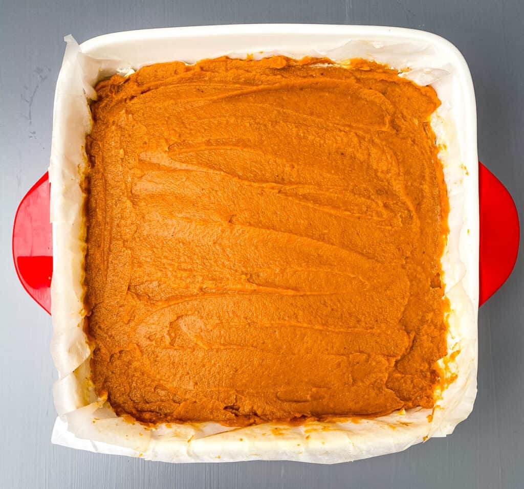 pumpkin cheesecake bars in red baking dish