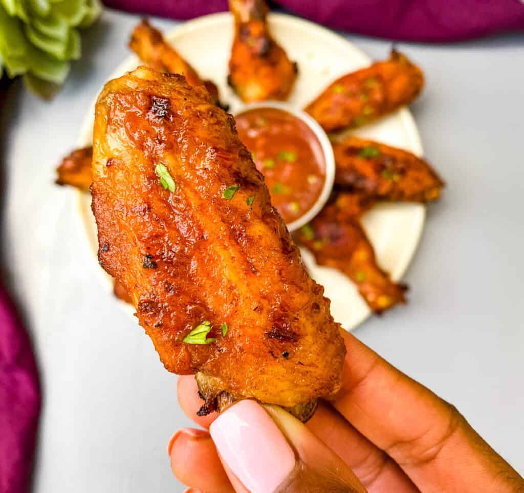 person holding air fryer bbq chicken wing