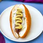 air fryer brats on a hotdog bun with mustard and onions