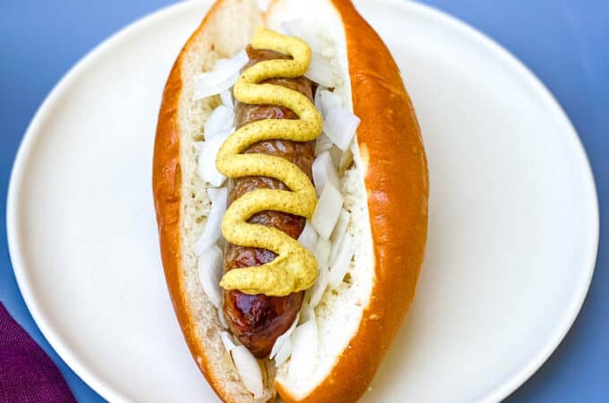air fryer brats on a hotdog bun with mustard and onions