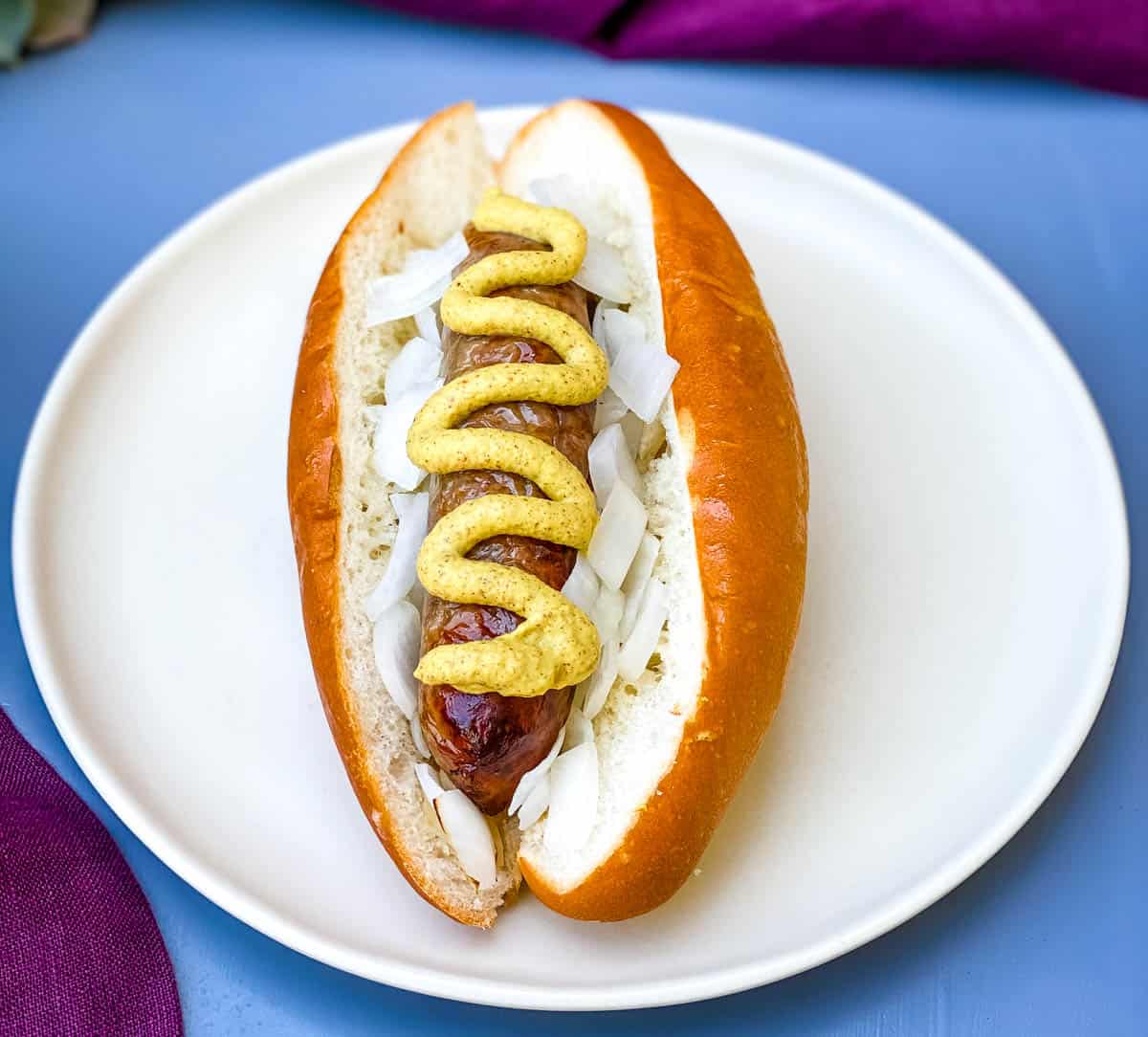 air fryer brats on a hotdog bun with mustard and onions