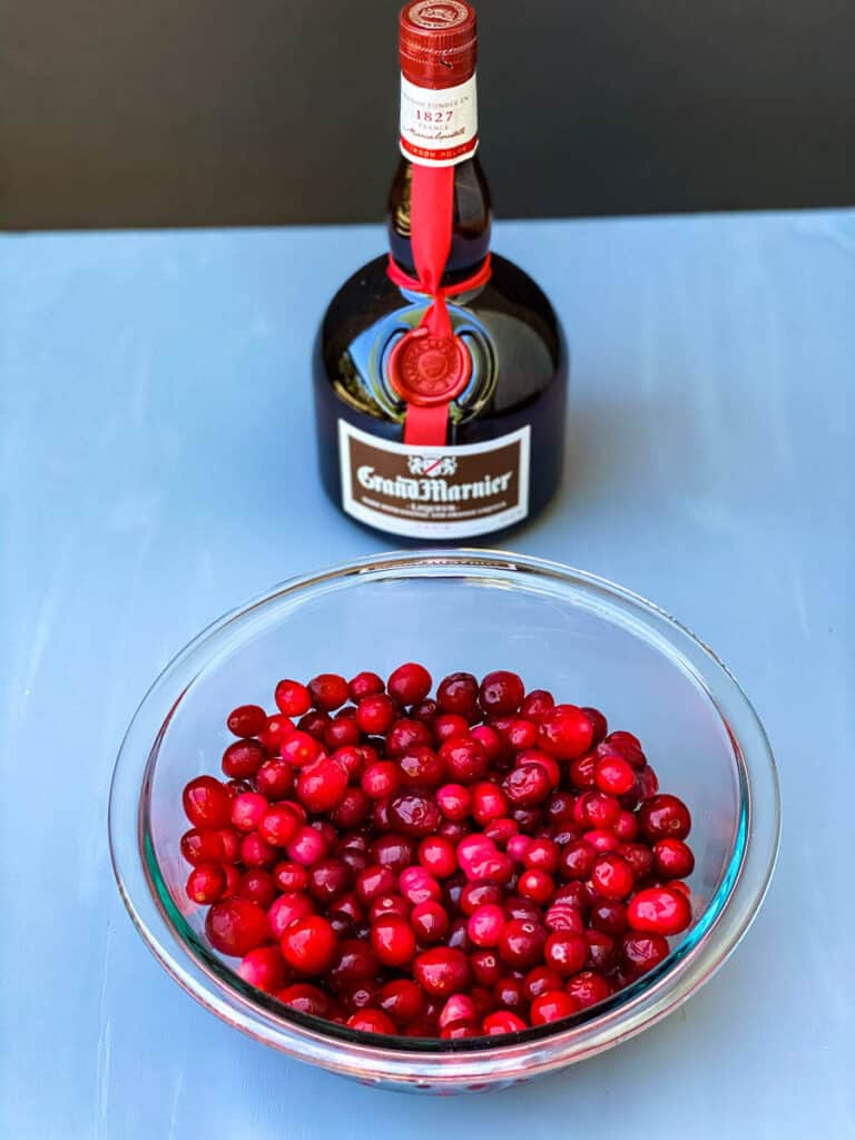 fresh or frozen cranberries in a glass bowl along with a bottle of Grand Marnier