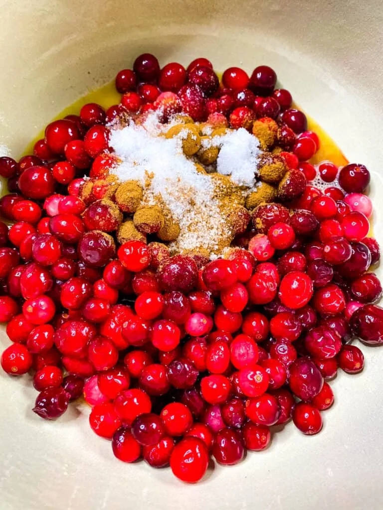 cranberries in a pot with cinnamon, honey, and sweetener