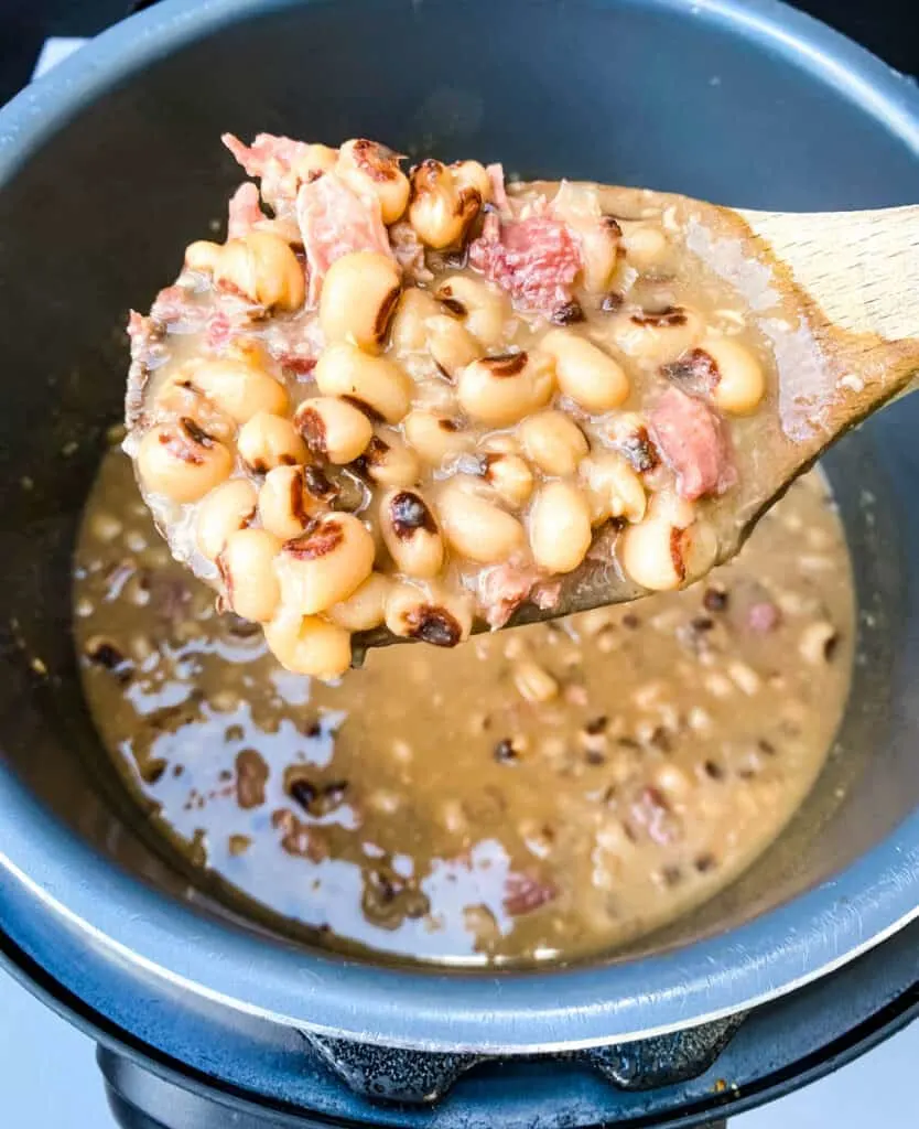 a wooden spoon of black eyed peas in an Instant Pot