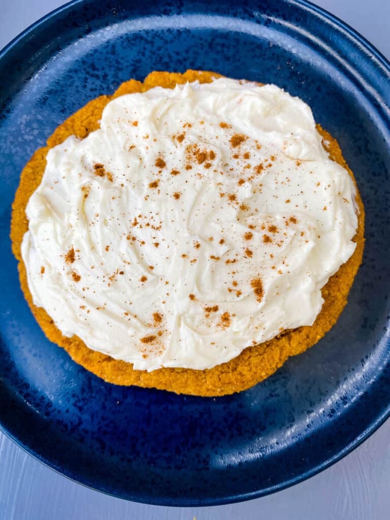 keto pumpkin cookies with cream cheese frosting and cinnamon on a blue plate