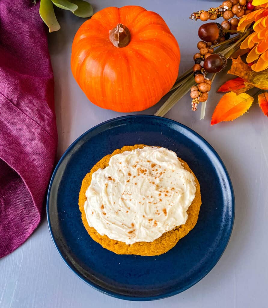 keto pumpkin cookies with cream cheese frosting and cinnamon on a blue plate