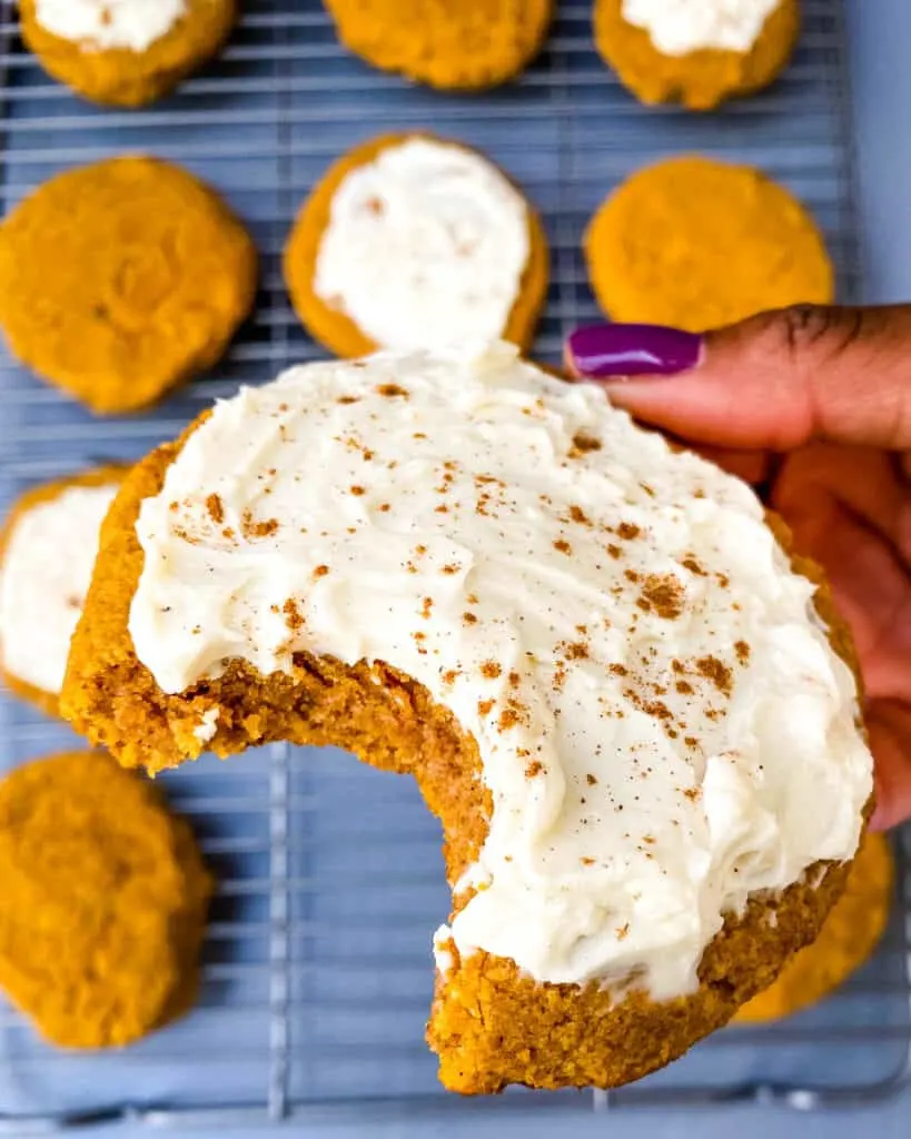 person holding keto pumpkin cookie with icing
