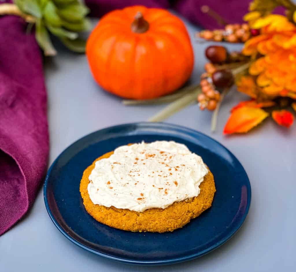 keto pumpkin cookies with cream cheese frosting and cinnamon on a blue plate