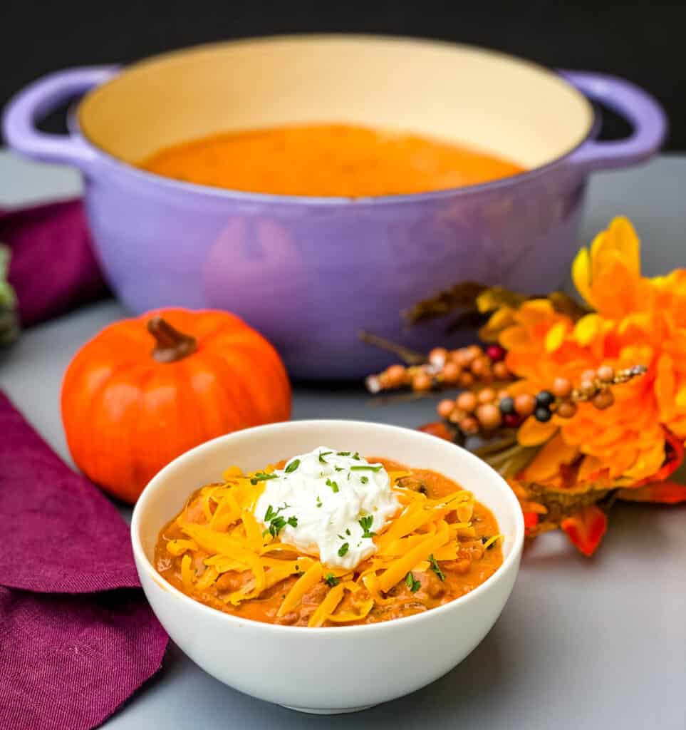 pumpkin chicken chili in a white bowl and chili in a purple Dutch oven