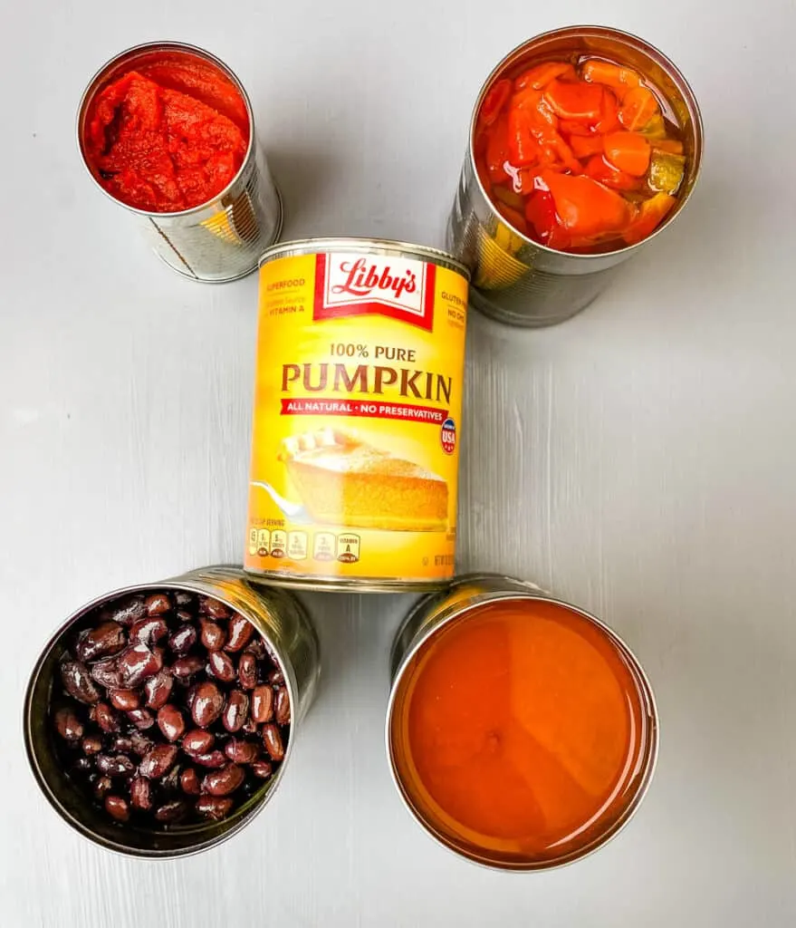 canned beans, tomatoes, and a can pumpkin on a flat surface