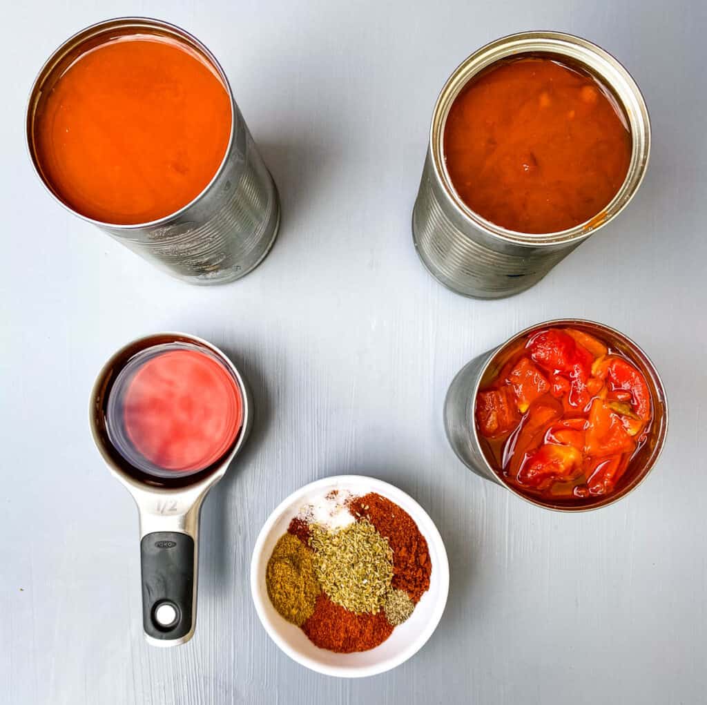 canned chili beans, broth, diced tomatoes and chili seasoning on a flat surface