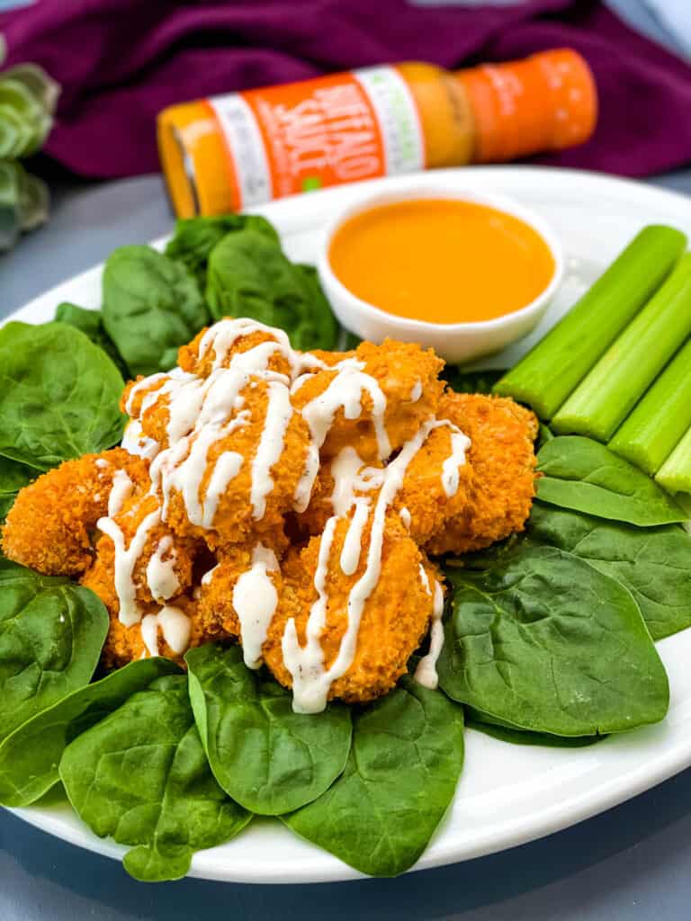 buffalo shrimp on a bed of lettuce with ranch with a bowl of buffalo sauce