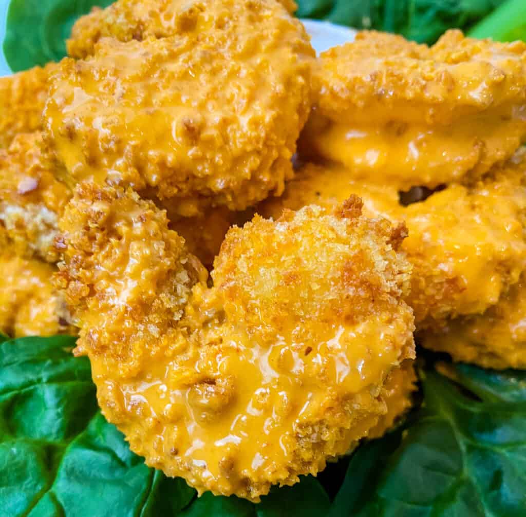 a piece of breaded buffalo shrimp on a bed of lettuce